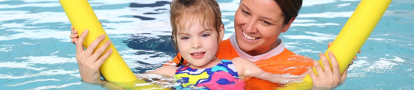 Child and swim teacher in swimming pool