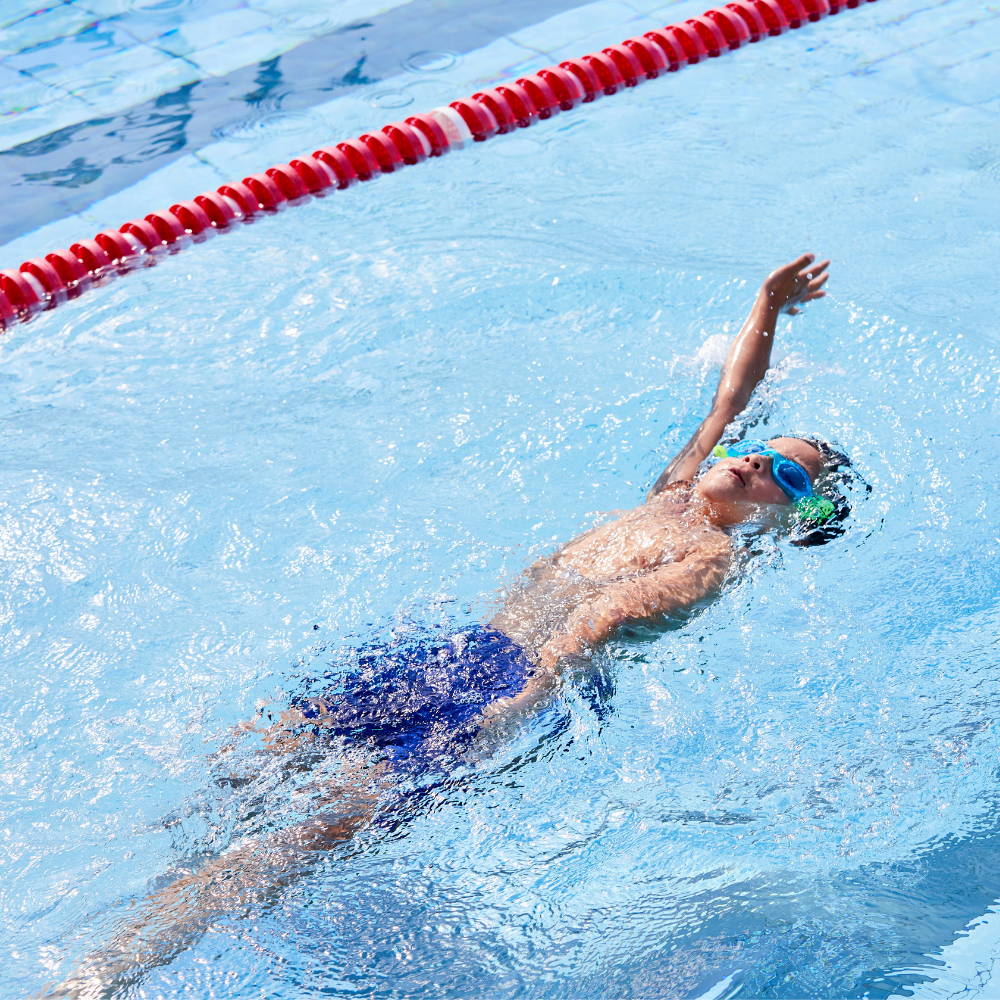 Young boy swimming backstroke in pool
