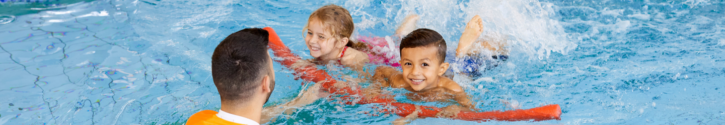 Two young children with swim teacher in swimming pool