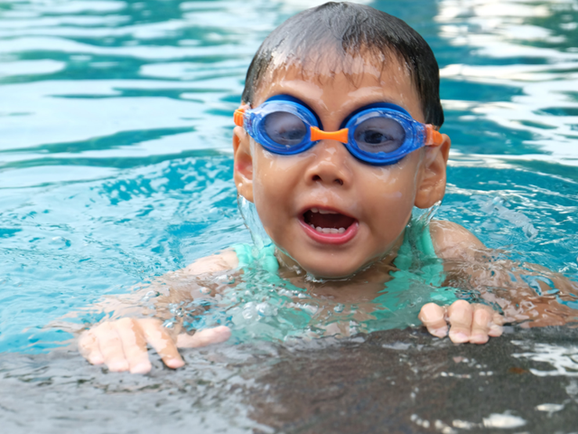 Young child in swimming pool with goggles