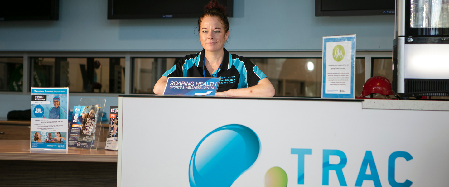 Staff member at reception desk smiling