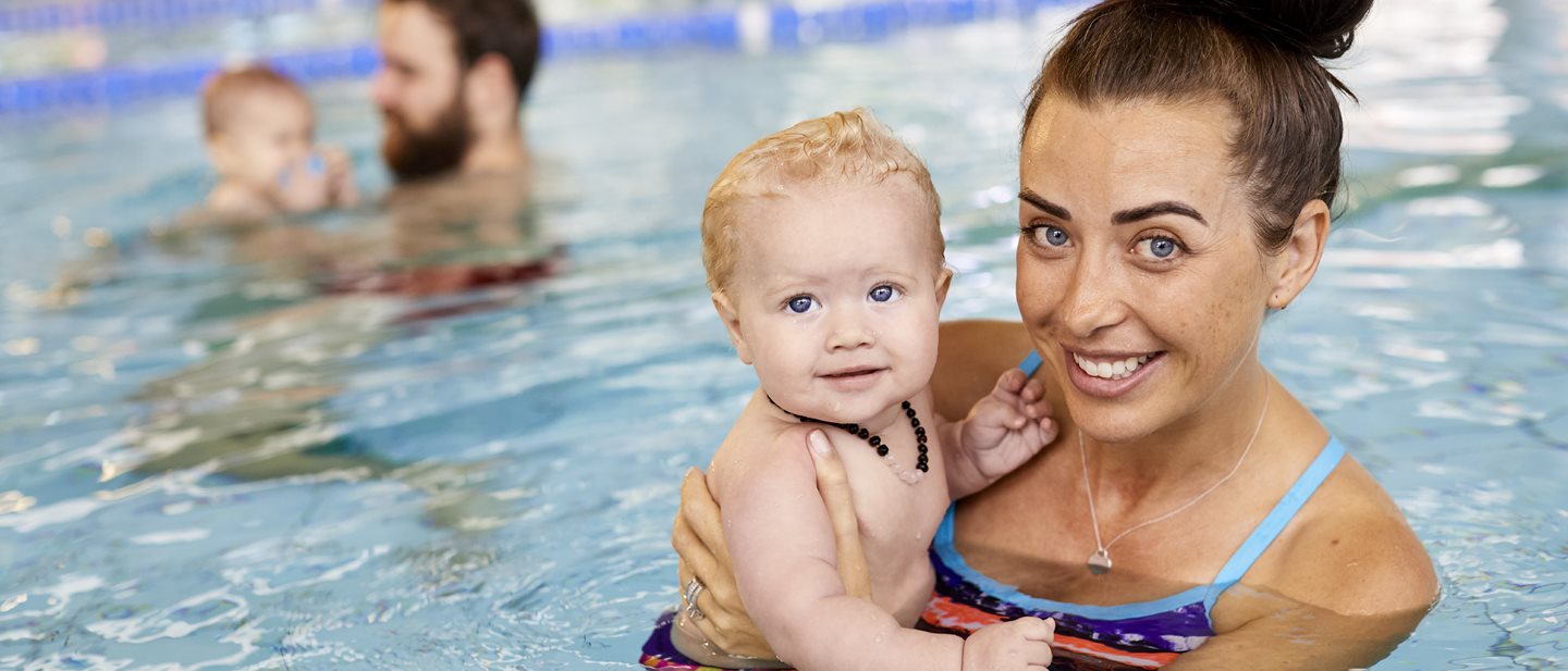 Mother holding toddler in swimming pool