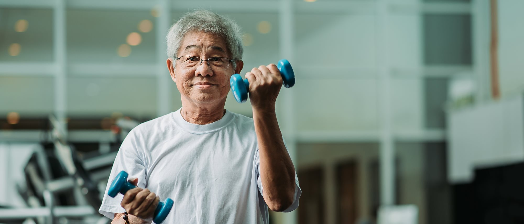 Senior man holding hand weights in gym