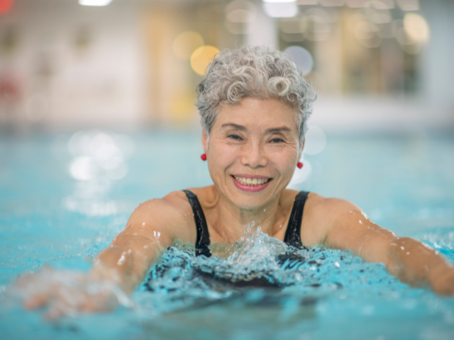 Woman in front of swimming pool wearing conservative swimwear