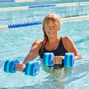 Woman smiling in swimming pool with aqua dumbbells